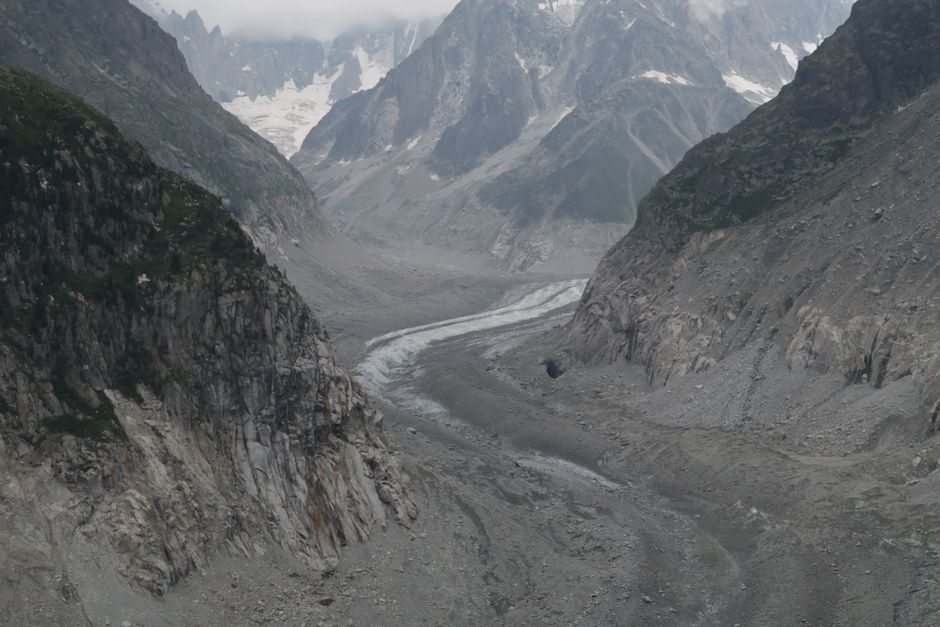 Stunning view of a rugged alpine valley with retreating glacier and rocky cliffs.